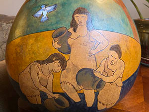 Close-up photo of a pot with a painted-on image of women holding water jugs
